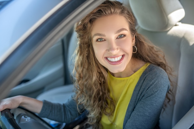 Gelukkige jonge glimlachende vrouw die een auto drijft