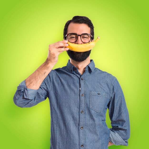 Gelukkige jonge hipster man met banaan op kleurrijke achtergrond