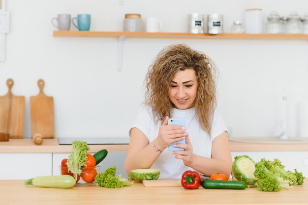 Gelukkige jonge huisvrouw die groentesalade mengt