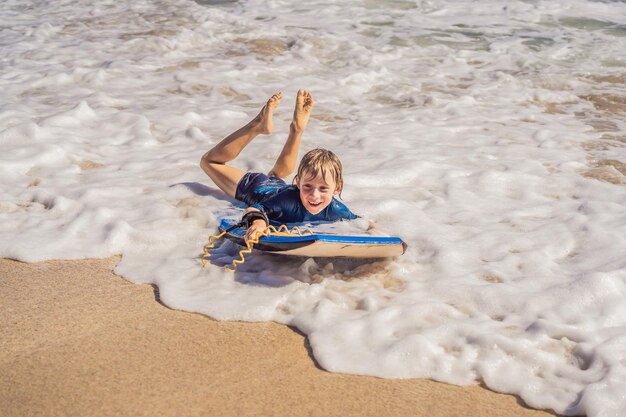 Gelukkige jonge jongen die plezier heeft op het strand op vakantie met Boogie board