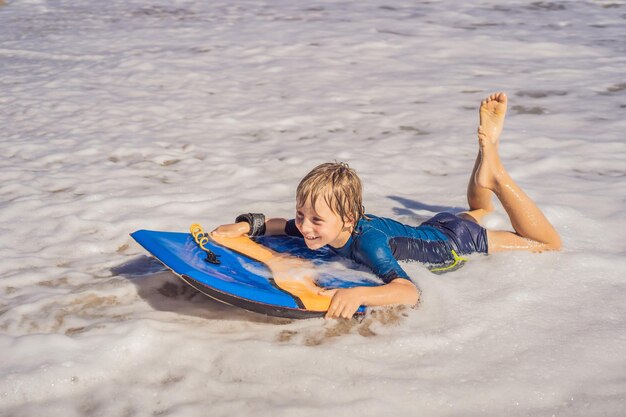 Gelukkige jonge jongen die plezier heeft op het strand op vakantie met Boogie board