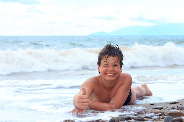 Gelukkige jonge jongen op het overzeese ok strand