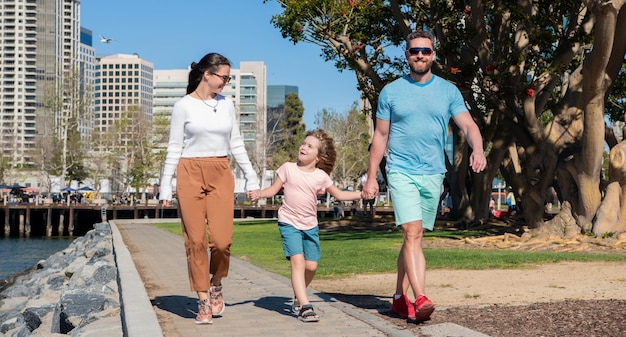 Gelukkige jonge mama en papa wandelen in het park met zoon, liefdadigheid.