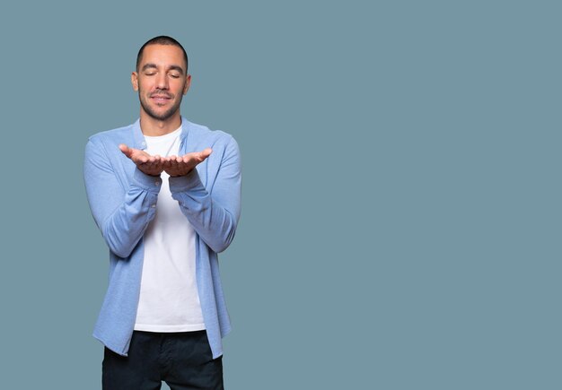 Gelukkige jonge man die iets met zijn hand vasthoudt
