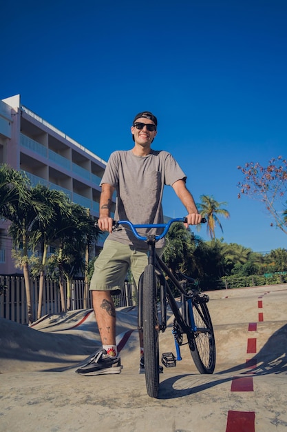 Gelukkige jonge man geniet van BMX rijden in het skatepark