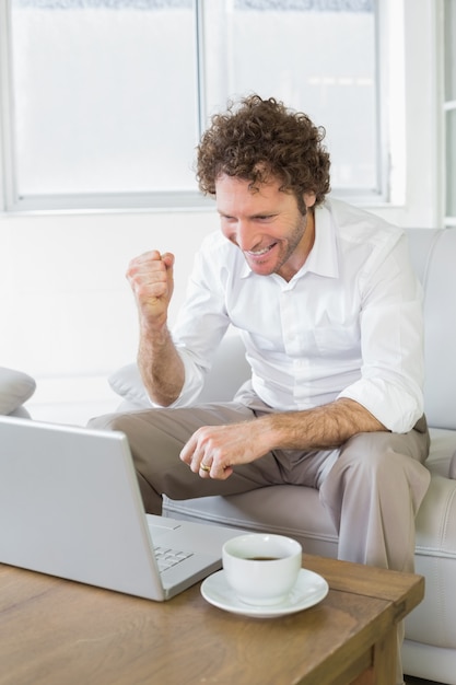 Gelukkige jonge man met laptop thuis