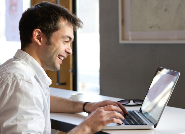 Gelukkige jonge man te typen op de laptop