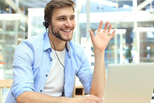 Gelukkige jonge mannelijke klantenservicemedewerker die op kantoor werkt.