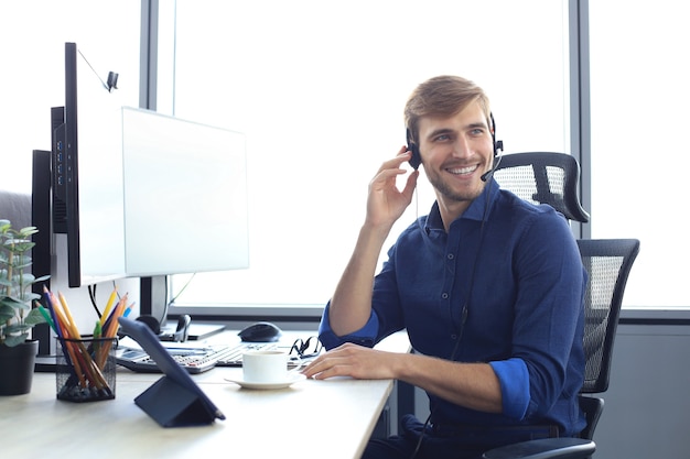 Foto gelukkige jonge mannelijke klantenservicemedewerker die op kantoor werkt.