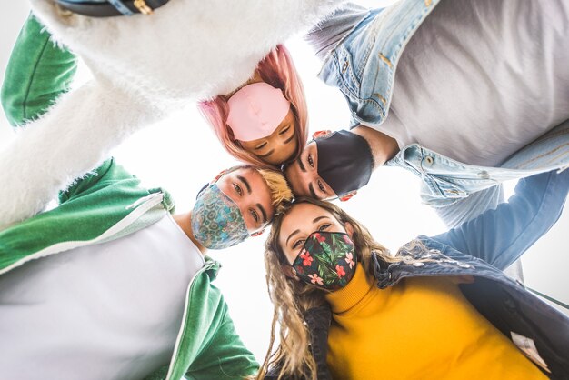 Gelukkige jonge mensen die buiten samenkomen en gezichtsmaskers dragen tijdens covid19 pandemie