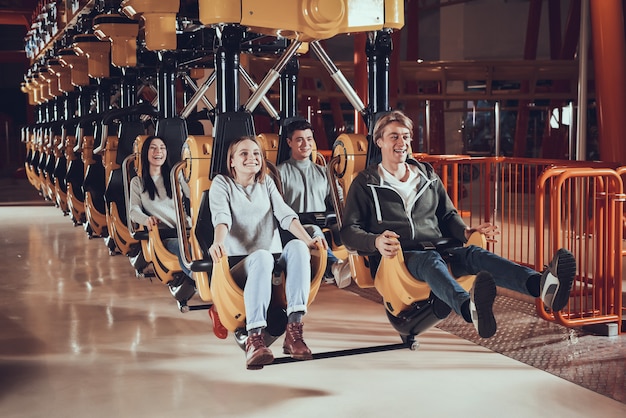 Gelukkige jonge mensen rijden op attracties.