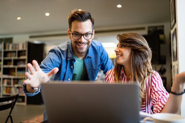 Gelukkige jonge mensen werken samen aan laptop. Teamwork, studie, technologie, zakelijk kantoorconcept