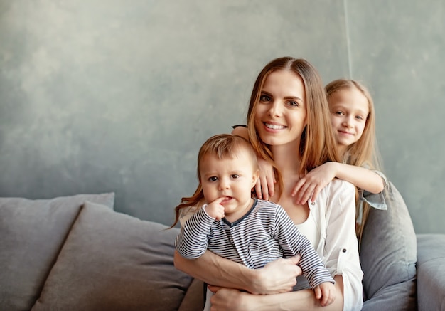 Gelukkige jonge moeder met haar kinderen hebben plezier thuis