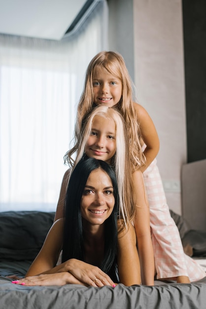 Gelukkige jonge moeder met twee dochters die op het bed rusten
