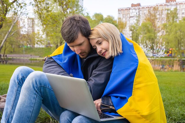 Gelukkige jonge Oekraïners gebruiken laptop buiten in het park Gratis lifestyle concept