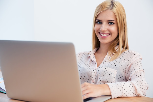 Gelukkige jonge onderneemster die laptop met behulp van