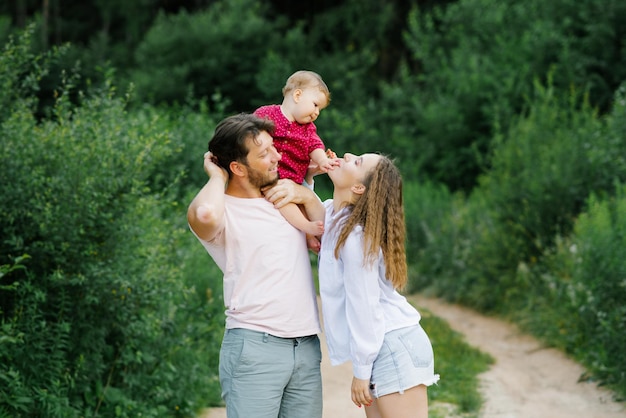 Gelukkige jonge ouders met een baby wandelen door het bos