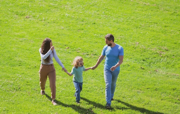 Gelukkige jonge ouders wandelen met kind buiten in het park Geluk en harmonie in het gezinsleven