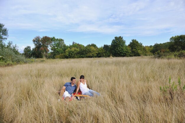 gelukkige jonge paar genieten van picknick op het platteland in het veld en veel plezier