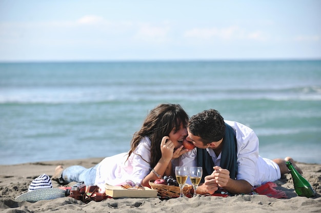 gelukkige jonge paar genieten van picknick op het strand en veel plezier op zomervakanties