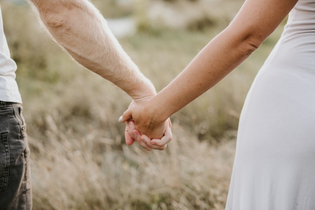 Gelukkige jonge paar hand in hand samen op de achtergrond van de natuur. liefde concept