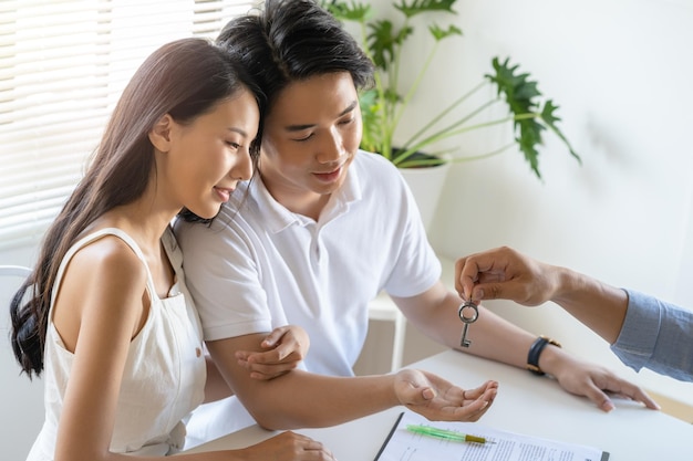 Gelukkige jonge paar man en vrouw krijgen de nieuwe huissleutels van de makelaar