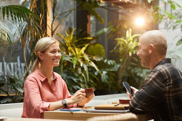 Gelukkige jonge paar met elkaar praten en koffie drinken tijdens datum in café