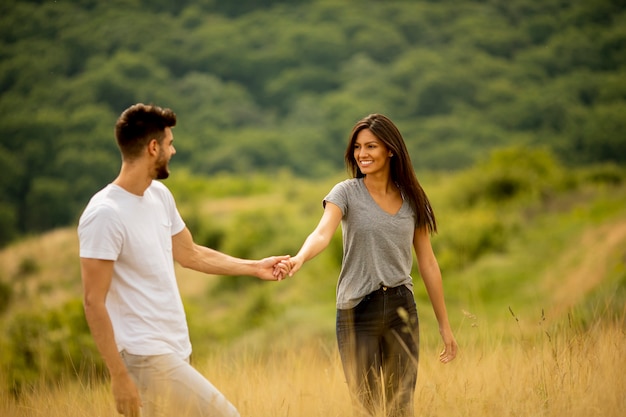 Gelukkige jonge paar verliefd wandelen door grasveld op een zomerdag