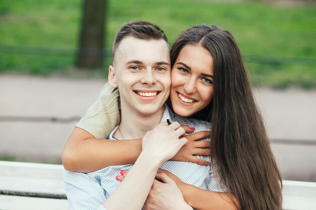 Gelukkige jonge paar verliefd zittend op een bankje en knuffelen