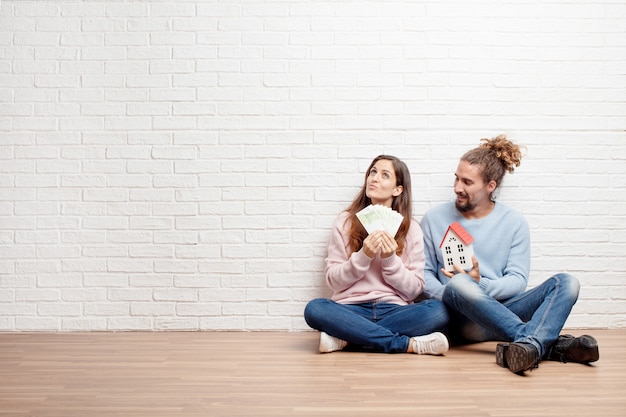 Gelukkige jonge paarzitting op de vloer van hun nieuw huis. conc