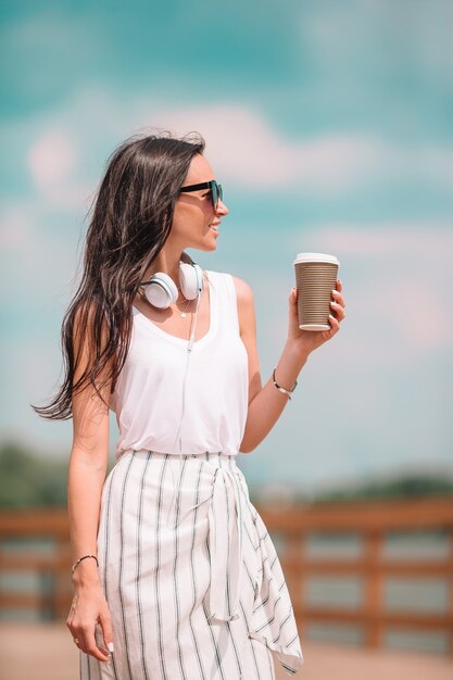 Gelukkige jonge stedelijke vrouw het drinken koffie in Europese stad.