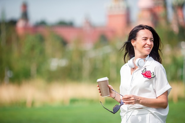 Gelukkige jonge stedelijke vrouw het drinken koffie in Europese stad.