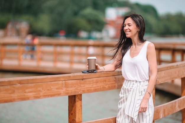 Gelukkige jonge stedelijke vrouw het drinken koffie in Europese stad.