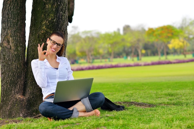 gelukkige jonge studentenvrouw met laptop in stadsparkstudie