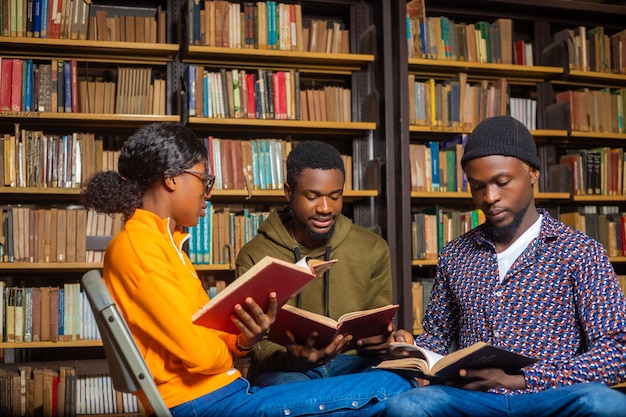 Gelukkige jonge universiteitsstudenten studeren met boeken in bibliotheek