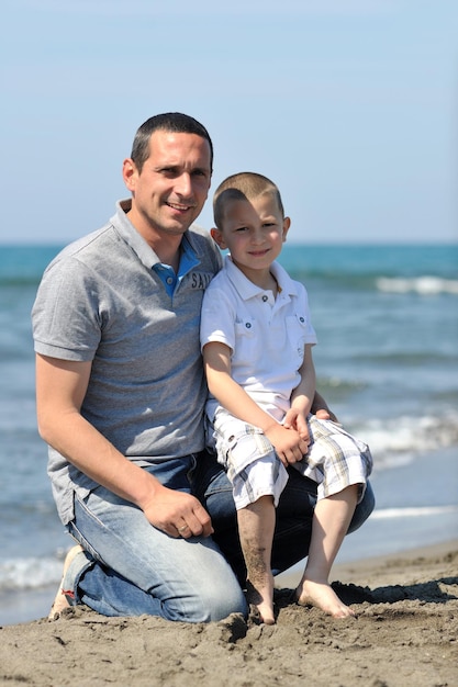 gelukkige jonge vader en zoon hebben plezier en genieten van tijd op het strand bij zonsondergang en vertegenwoordigen een gezond gezin en ondersteuningsconcept