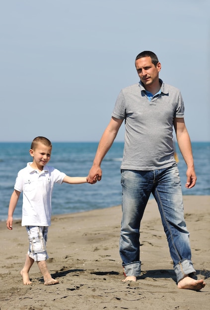 gelukkige jonge vader en zoon hebben plezier en genieten van tijd op het strand bij zonsondergang en vertegenwoordigen een gezond gezin en ondersteuningsconcept