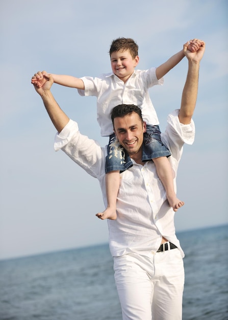 gelukkige jonge vader en zoon hebben plezier en genieten van tijd op het strand bij zonsondergang en vertegenwoordigen een gezond gezin en ondersteuningsconcept