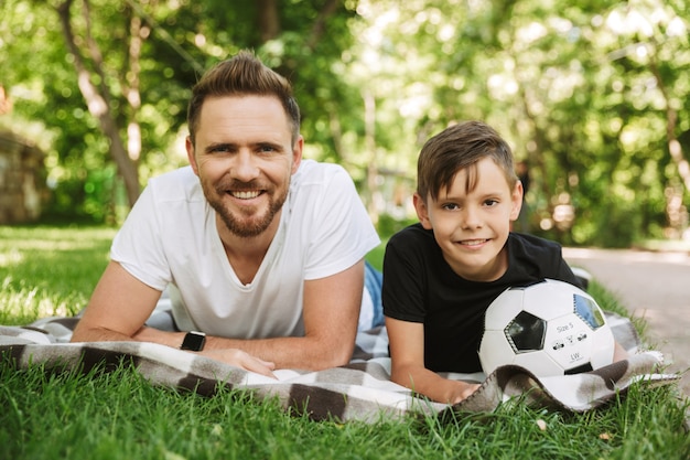 Gelukkige jonge vader met zijn zoontje met voetbal