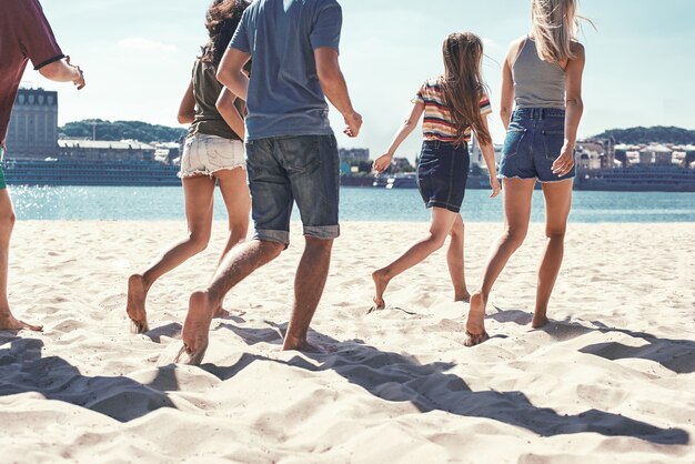 Gelukkige jonge vriendengroep veel plezier en vieren tijdens het springen en rennen op het strand