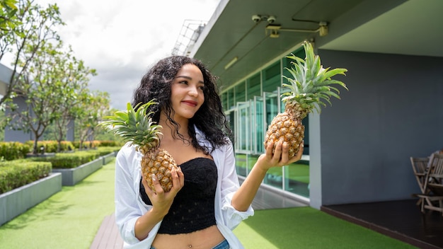 Gelukkige jonge vrouw die ananas toont Ananas fruit vrouw die lacht gezond en vrolijk Mixedrace Aziatisch Kaukasisch model met ananas