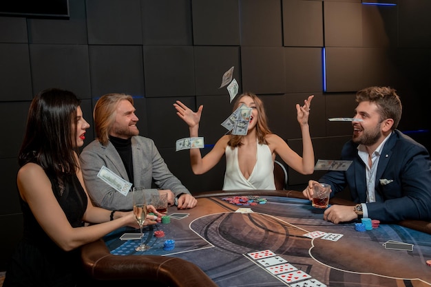 Gelukkige jonge vrouw die bankbiljetten in de lucht gooit terwijl ze pokerspel wint