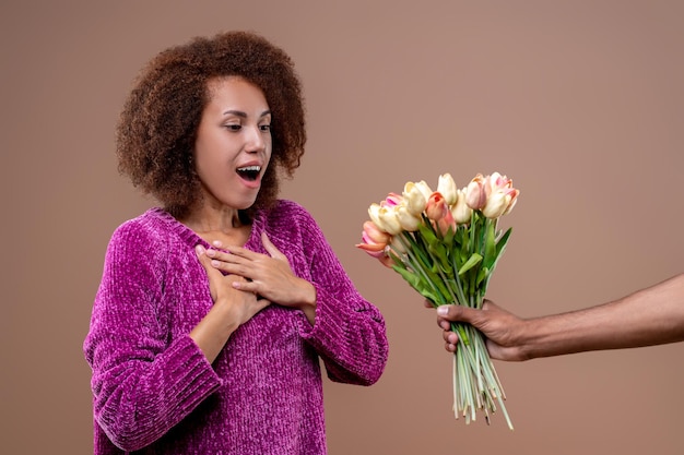 Gelukkige jonge vrouw die bloemen ontvangt en tevreden kijkt