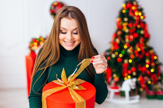 Gelukkige jonge vrouw die de doos van de kerstmisgift opent