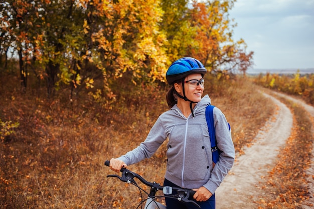 Gelukkige jonge vrouw die een fiets op dalingsgebied berijden