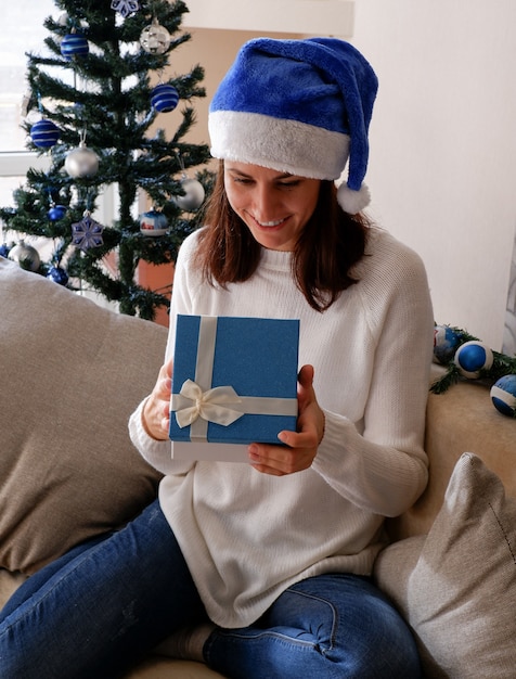 Gelukkige jonge vrouw die een kerstcadeaudoos opent