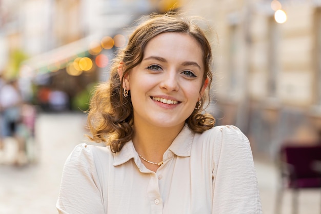 Gelukkige jonge vrouw die glimlacht, wegkijkt, droomt, rust, goed nieuws, zich tevreden voelt in de straat van de stad.