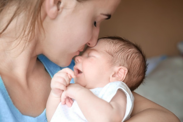 Gelukkige jonge vrouw die haar pasgeboren babyjongen close-up kust