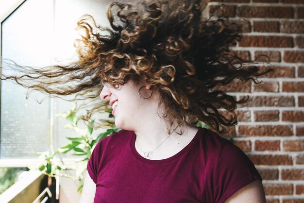 Foto gelukkige jonge vrouw die haar tegen de muur gooit.