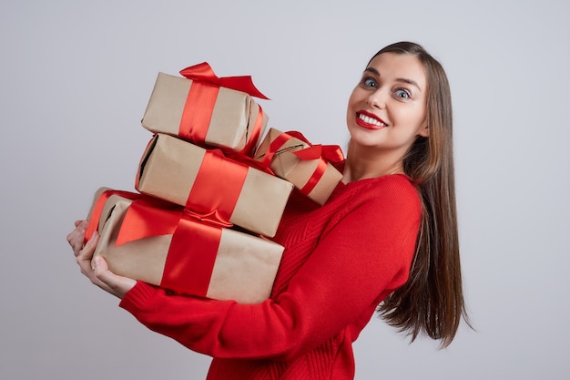 Gelukkige jonge vrouw die in een rode sweater een paar giftdoos houdt